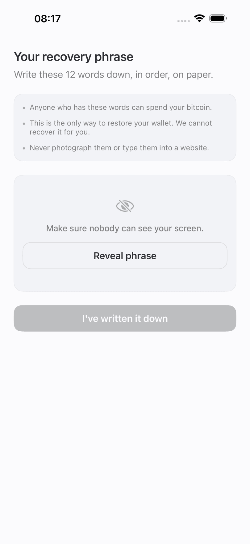 ₿21 Wallet recovery phrase screen on iPhone, the 12 words still hidden behind a Reveal phrase button, warning that anyone holding them can spend your bitcoin